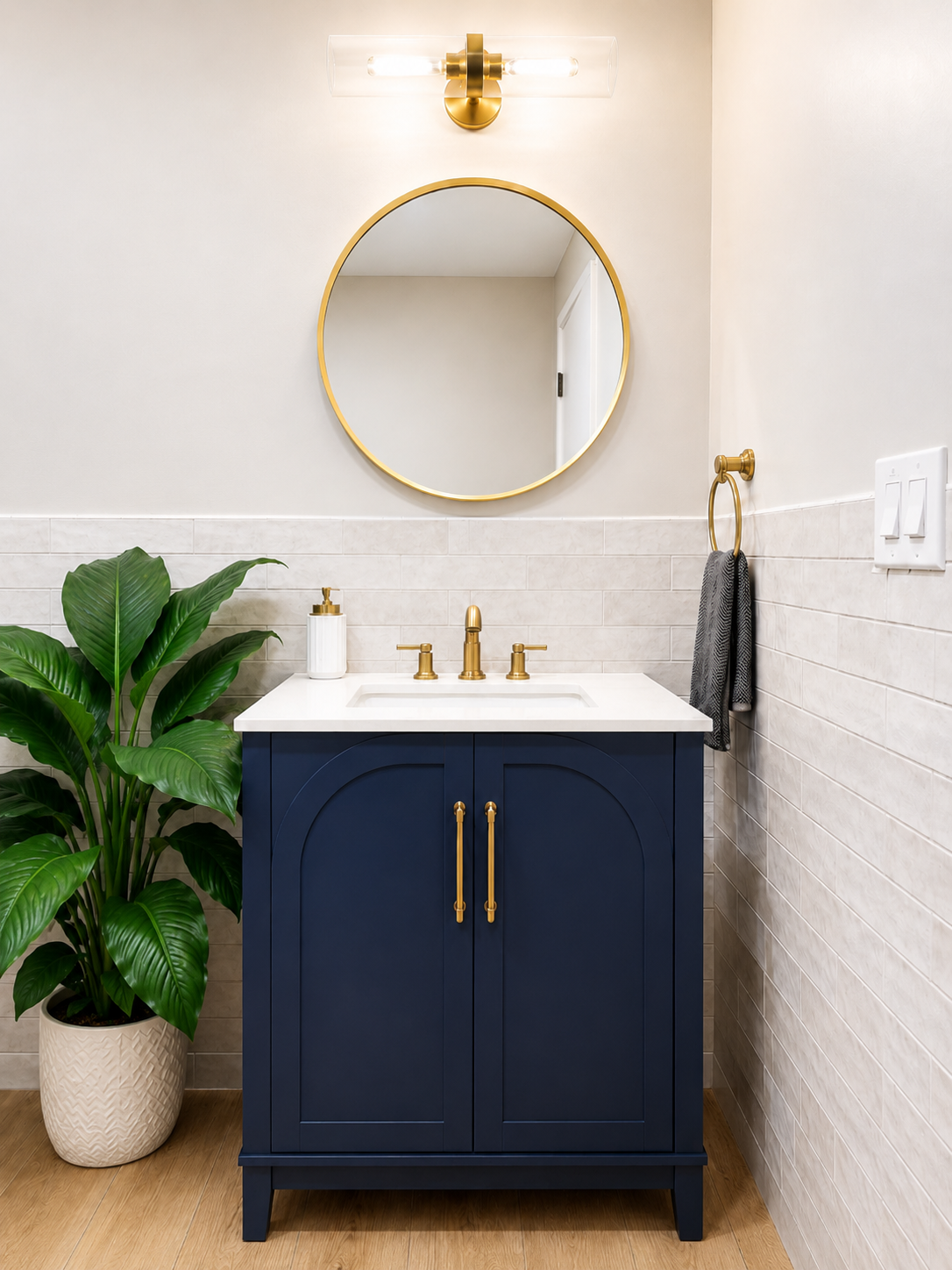 ADA bathroom with gold grab bars, toilet, and potted plant on wood-look floor